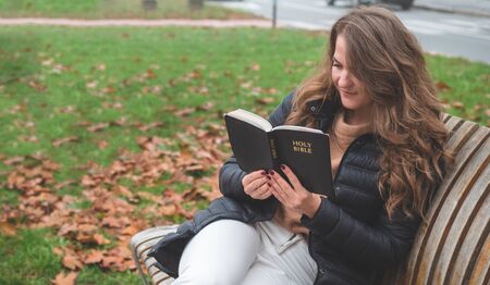 Women in outdoors reading Bible. Concept for faith, spirituality and religion. Peace, hopeの写真素材