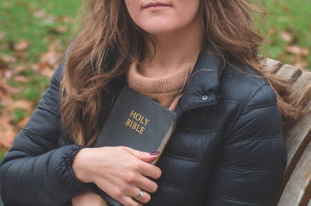 Women in outdoors reading Bible. Concept for faith, spirituality and religion. Peace, hopeの写真素材