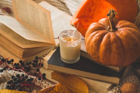 Still life details in home interior of living room. Sweaters and cup of coffee with pumpkins and autumn decor on the books. Read, Rest. Cozy autumn or winter concept.の写真素材