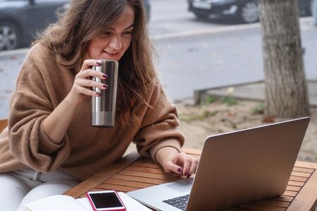 Happy young girl working at a coffee shop with a laptop.の写真素材