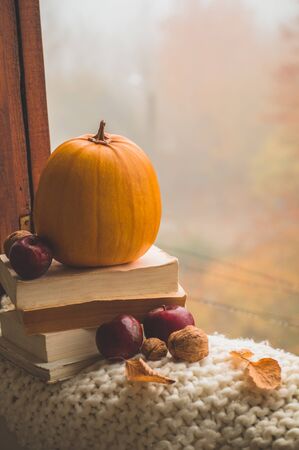 Sweet Home. Still life details in home on a wooden window. Sweaters and candle,  autumn decor on the books. Read, Rest. Cozy autumn or winter concept.の写真素材