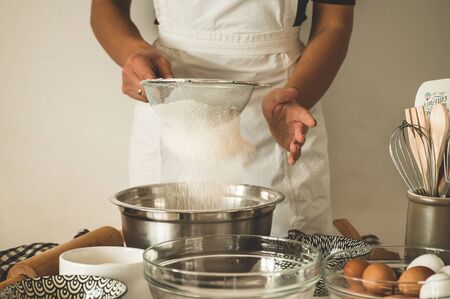 Woman adds some flour to dough on wooden table. Woman hands kneading fresh dough. Concept ingredients for cooking flour products or dough. Rural or rustic style.の写真素材