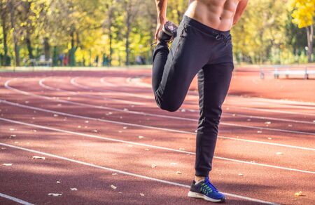 Male model with muscular fit and slim body at the city stadium. Healthy lifestyle