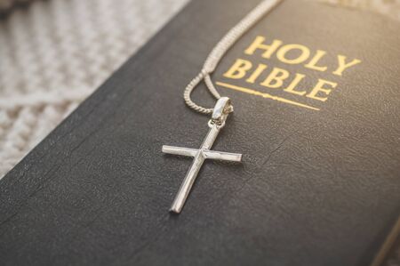 The Bible and the cross lie on a warm sweater. Concept for faith, spirituality and religion. Peace,...