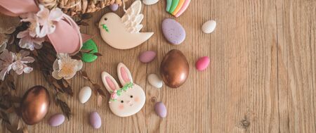 Happy Easter. Multicolored pastel easter cookies in a wicker basket  on a wood background. Easter...
