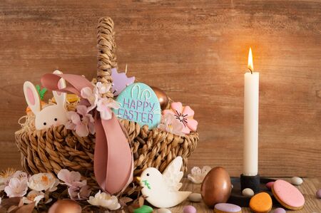 Happy Easter. Multicolored pastel easter cookies in a wicker basket  on a wood background. Easter conceptの写真素材