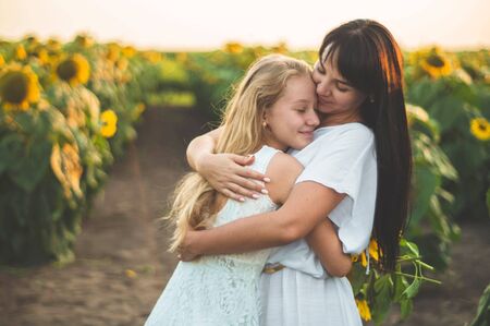Happy mother and her teenager daughter in the sunflower field. Outdoors lifestyle happiness. Summer fun. Mothers Day conceptsの写真素材