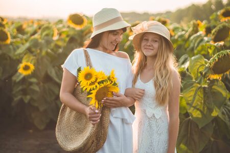 Happy mother and her teenager daughter in the sunflower field. Outdoors lifestyle happiness. Summer fun. Mothers Day conceptsの写真素材