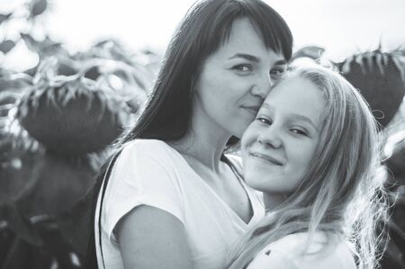 Happy mother and her teenager daughter in the sunflower field. Outdoors lifestyle happiness. Summer fun. Mothers Day conceptsの写真素材