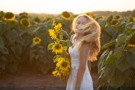 Beautiful young woman in a sunflower field. Portrait of a young woman in the sun. Pollen allergies concept. Outdoors lifestyle happiness. Summer.の写真素材
