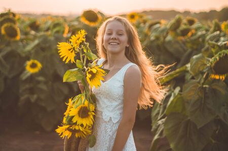 Beautiful young woman in a sunflower field. Portrait of a young woman in the sun. Pollen allergies concept. Outdoors lifestyle happiness. Summer.の写真素材