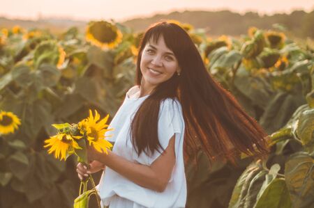 Beautiful young woman in a sunflower field. Portrait of a young woman in the sun. Pollen allergies concept. Outdoors lifestyle happiness. Summer.の写真素材