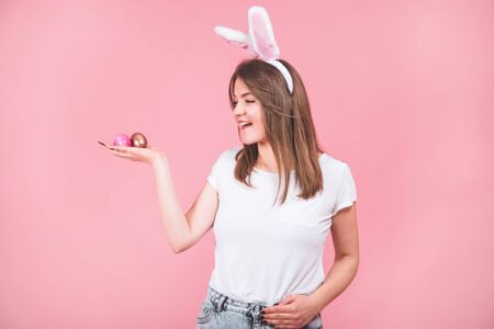 Happy Easter. Portrait of a pretty lovely girl wearing bunny ears standing isolated over pink...