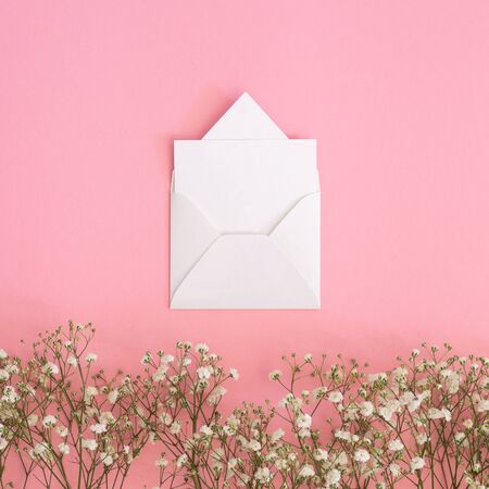 Blank greeting card, Kraft envelope  and gypsophila flowers on a pink background. Flat lay, top view.の写真素材