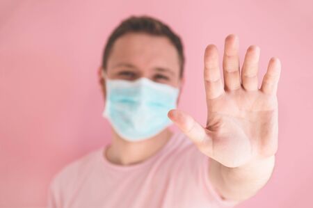 A man in a viral mask on a pink background, wearing face protection in prevention for coronavirus. COVID-19 Pandemic Coronavirusの写真素材