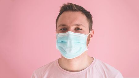 A man in a viral mask on a pink background, wearing face protection in prevention for coronavirus....