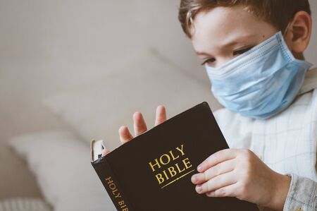 Coronavirus covid-19. The child holds a bible. Bible readings and prayer. Peace, hope concept.の写真素材