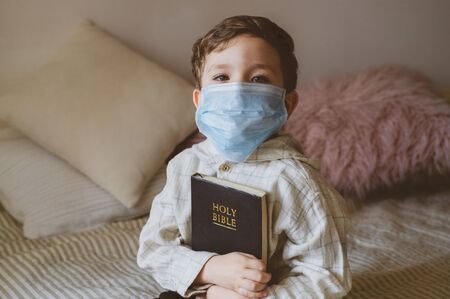 Coronavirus covid-19. The child holds a bible. Bible readings and prayer. Peace, hope concept.