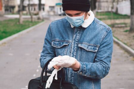 A man in a viral mask puts on protective gloves. Protection in prevention for coronavirus. COVID-19 Pandemic Coronavirusの写真素材