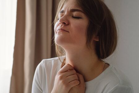 Women closed her eyes, praying in a in the living room. Hands folded in prayer concept for faith,...