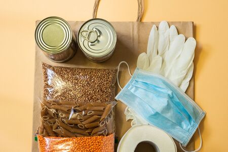 Food delivery, Donation, coronavirus. Buckwheat, pasta, canned food, lentils, toilet paper, mask and rubber gloves. View from aboveの写真素材
