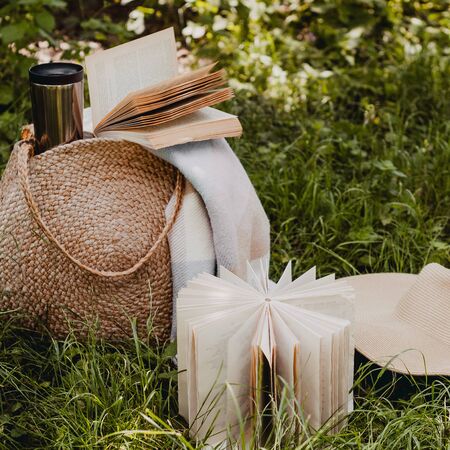 Straw bag, book, hat and thermo cup on a sunny summer day.の写真素材