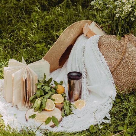 Straw bag, book, hat, flowers, lemonade and fresh lemons a sunny summer day.の写真素材