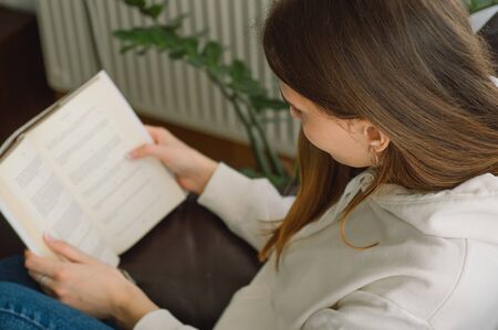 Reading and development. Beauty young woman is reading a book at home. Thoughtful girl reading...
