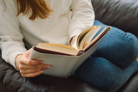 Reading and development. Beauty young woman is reading a book at home. Thoughtful girl reading important book.の写真素材