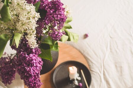 Still life details in home interior of living room. Lilac flowers with hot cup tea. Cozy spring concept.の写真素材