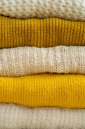 Pile of knitted clothes yellow white color. Autumn winter concept. Copy Space.の写真素材