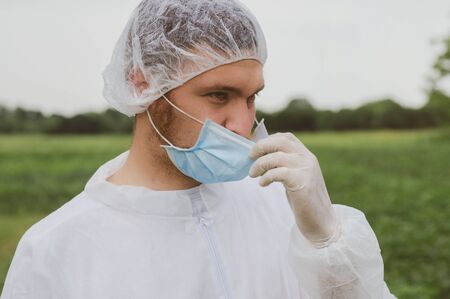 A man adjusts a mask on his face in the outdoors. Quarantine, world pandemic, COVID-19, coronavirus,...