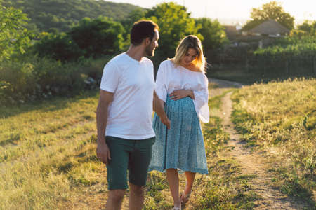 Happy and young pregnant couple in outdoors.