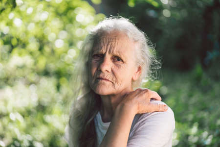 Portrait of a gray-haired adult grandmother against the background of nature.