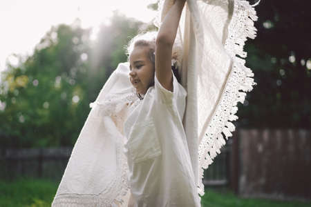 Happy child. Funny girl playing with a blanket. Smiling child girl. Cheerful hild outdoors in nature.の写真素材