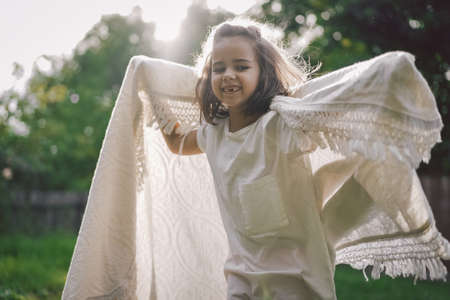Happy child. Funny girl playing with a blanket. Smiling child girl. Cheerful hild outdoors in nature.の写真素材