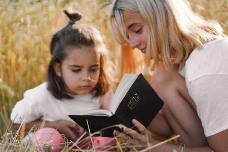 Girls reading holy bible in a wheat field. Study the holy bible together.の写真素材