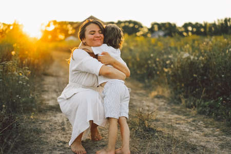 Woman playing with her child on the field during sunset.の写真素材