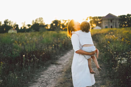Woman playing with her child on the field during sunset.の写真素材