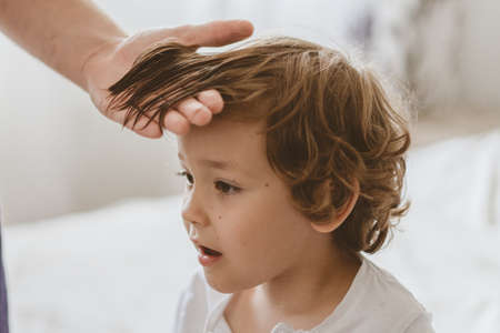 Father cuts her son hair in the room. Family during quarantine, Scissors and a comb in male hands....