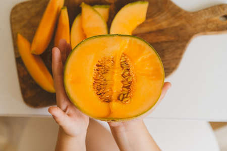 Cute beautiful little boy eating fresh melon. Healthy food, childhood and development. Happy kid at home.の写真素材