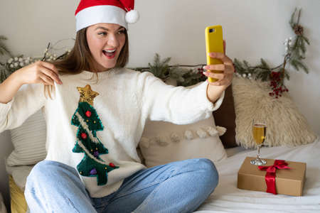 Girl showing her Christmas sweater through a video call to friends. Quarantine. Self-isolation....