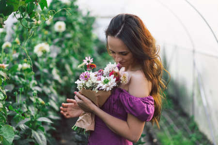 Portrait girl with long hair in the greenhouse. Walk in the flower garden. Girl and flowers. Floristics.の写真素材