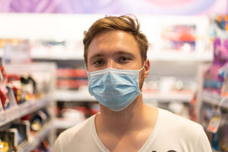 The man wears a protective mask in the store. Safety, health protection during COVID-19 quarantine.の写真素材