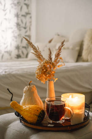 Still life details in home interior of living room. Pumpkin and cup of tea with candles on a serving...