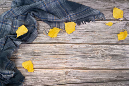 Autumn flat lay with gray scarf and dry leaves of yellow color on wood background. Fall seasonの写真素材