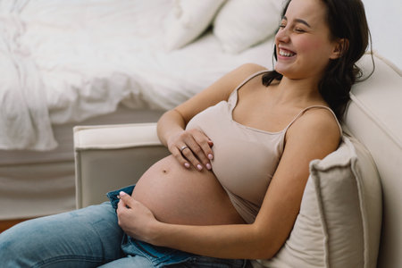 Attractive pregnant woman is sitting in armchair and holding her belly. Last months of pregnancy.の写真素材