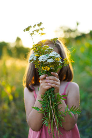 Portrait of a little girl with flowers in the field. lifestyleの写真素材
