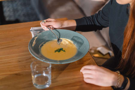 Beautiful girl eating chees sup in cafe indoorsの写真素材