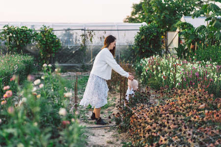 Woman playing with her child in a greenhouse with flowers. Happy mother's day